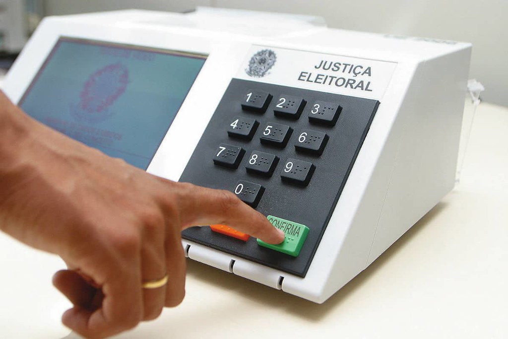 index finger presses confirm button on electronic voting machine