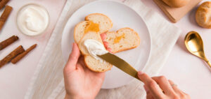 top-view-woman-spreading-cream-cheese-on-bread-aspect-ratio-930-440