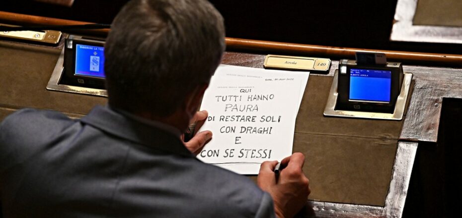 M5S senator Alberto Airola writes a banner reading "Everyone here is afraid to be alone with Draghi and themselves" in the Senate hall before a vote of confidence to the prime minister at Palazzo Madama in Rome, on July 14, 2022. - On 14 July, Mario Draghi will face a vote of confidence on a number of decree-laws in the Senate, seeking the Senate's support for his government in the balance due to Giuseppe Conte's M5S (Movimento 5 Stelle) party opting out of vote. (Photo by Andreas SOLARO / AFP)