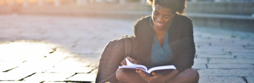 young-black-woman-street-reads-book-scaled-aspect-ratio-930-440