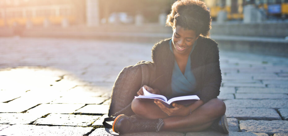 young-black-woman-street-reads-book-scaled-aspect-ratio-930-440